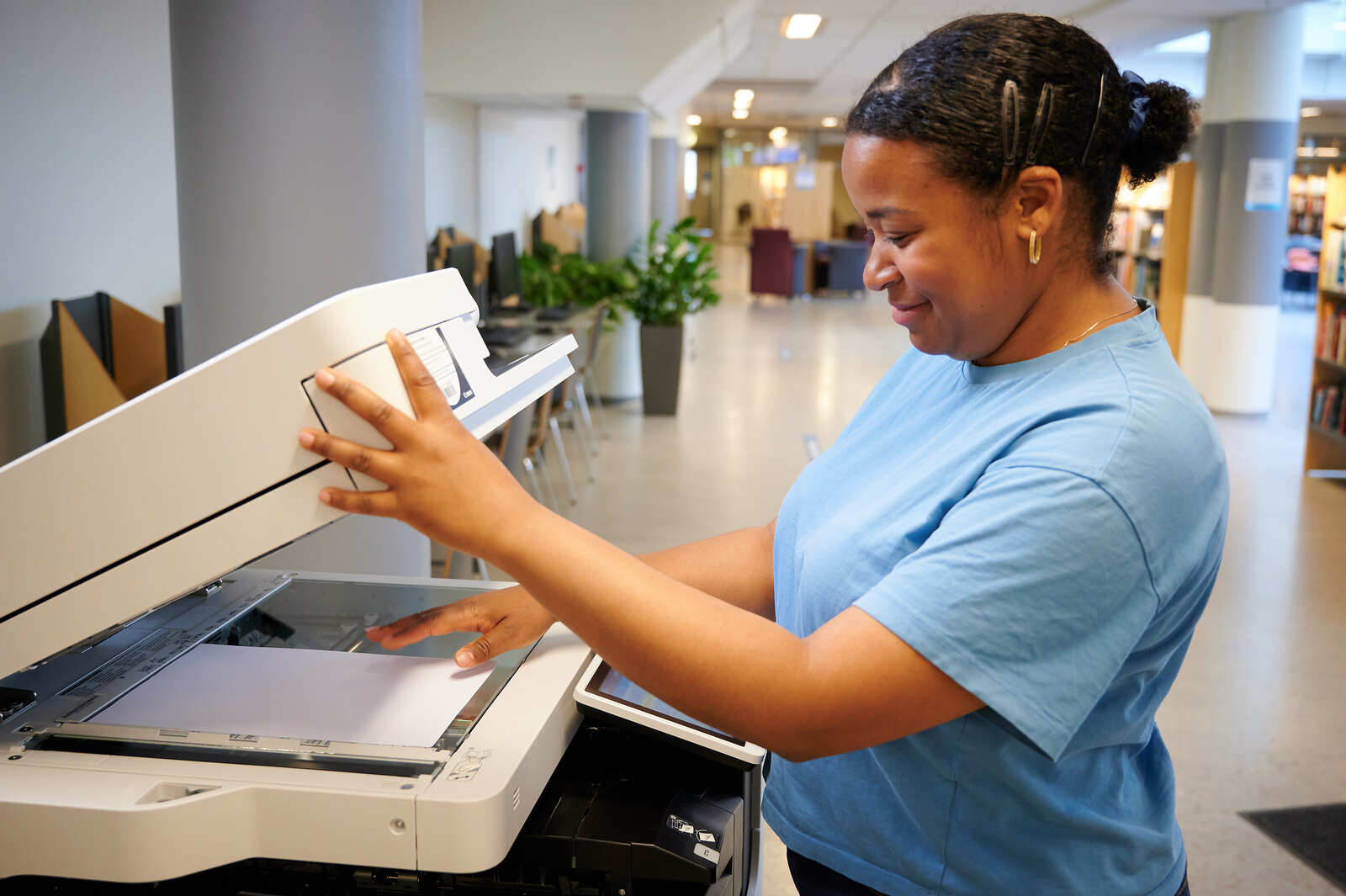 Dame som kopierer papirer på kopimaskin