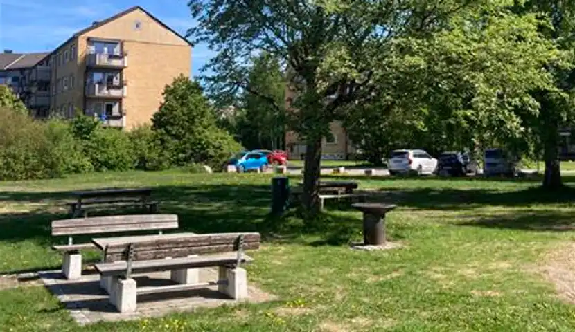 Et par benker midt i en park og en grillplass.