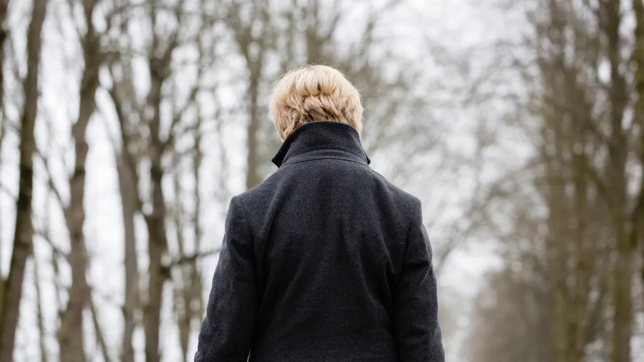 En kvinne som går langs en sti i skogen.