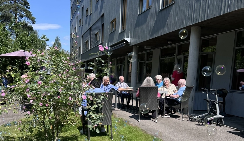 En gruppe mennesker som sitter ved et bord utenfor en bygning.