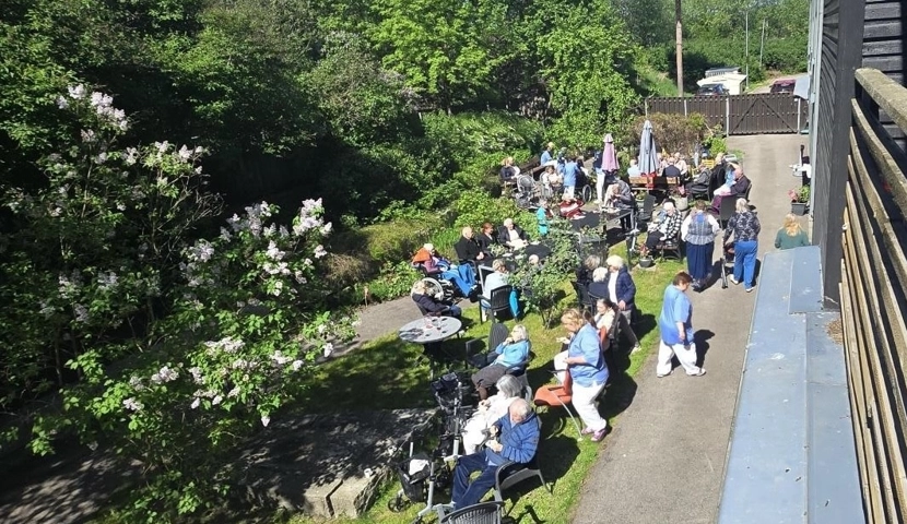 En gruppe mennesker som sitter på en benk ved siden av en skog.