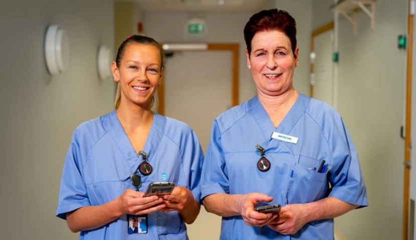 To sykepleiere smiler til kameraet.