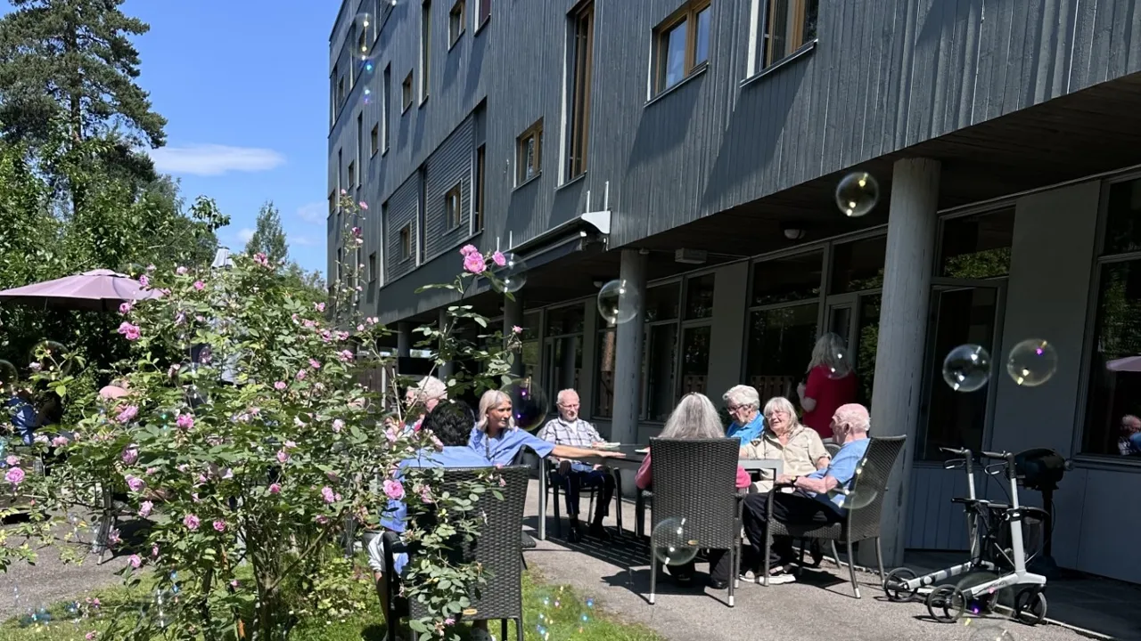 En gruppe mennesker som sitter ved et bord utenfor en bygning.