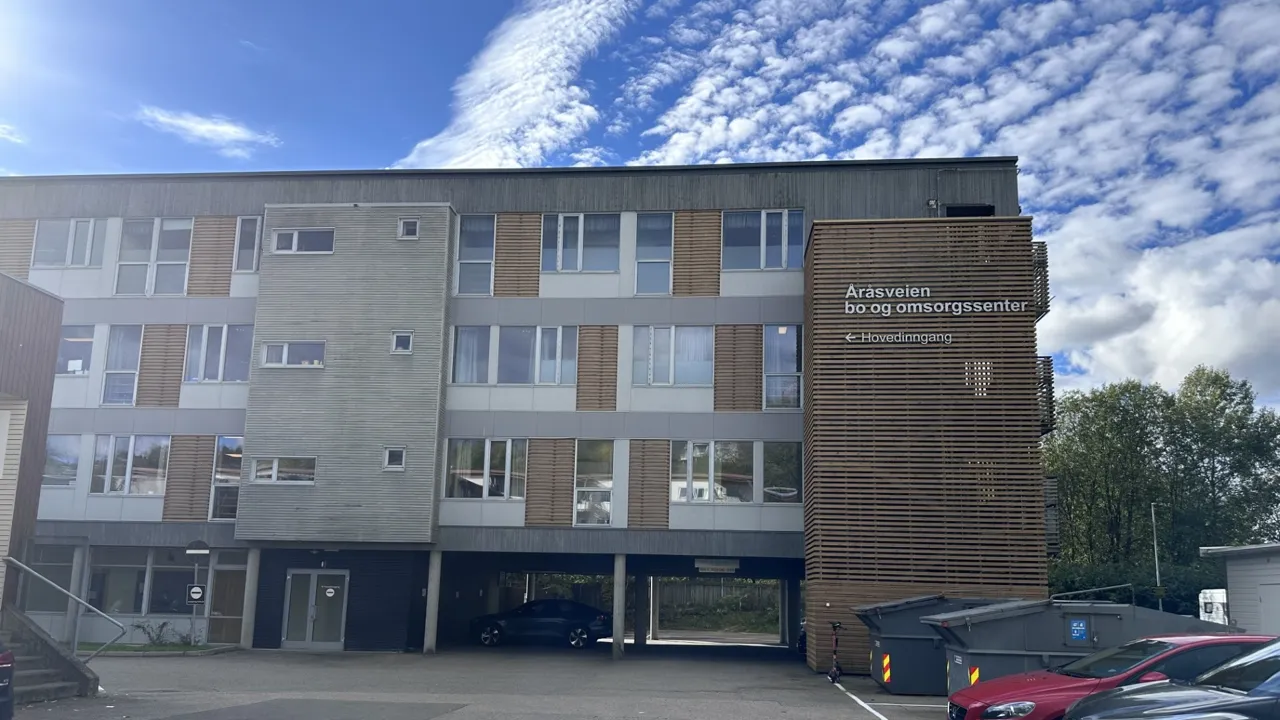 En parkeringsplass med biler parkert foran en bygning.