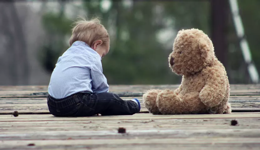 Barn sitter på bro med en bamse