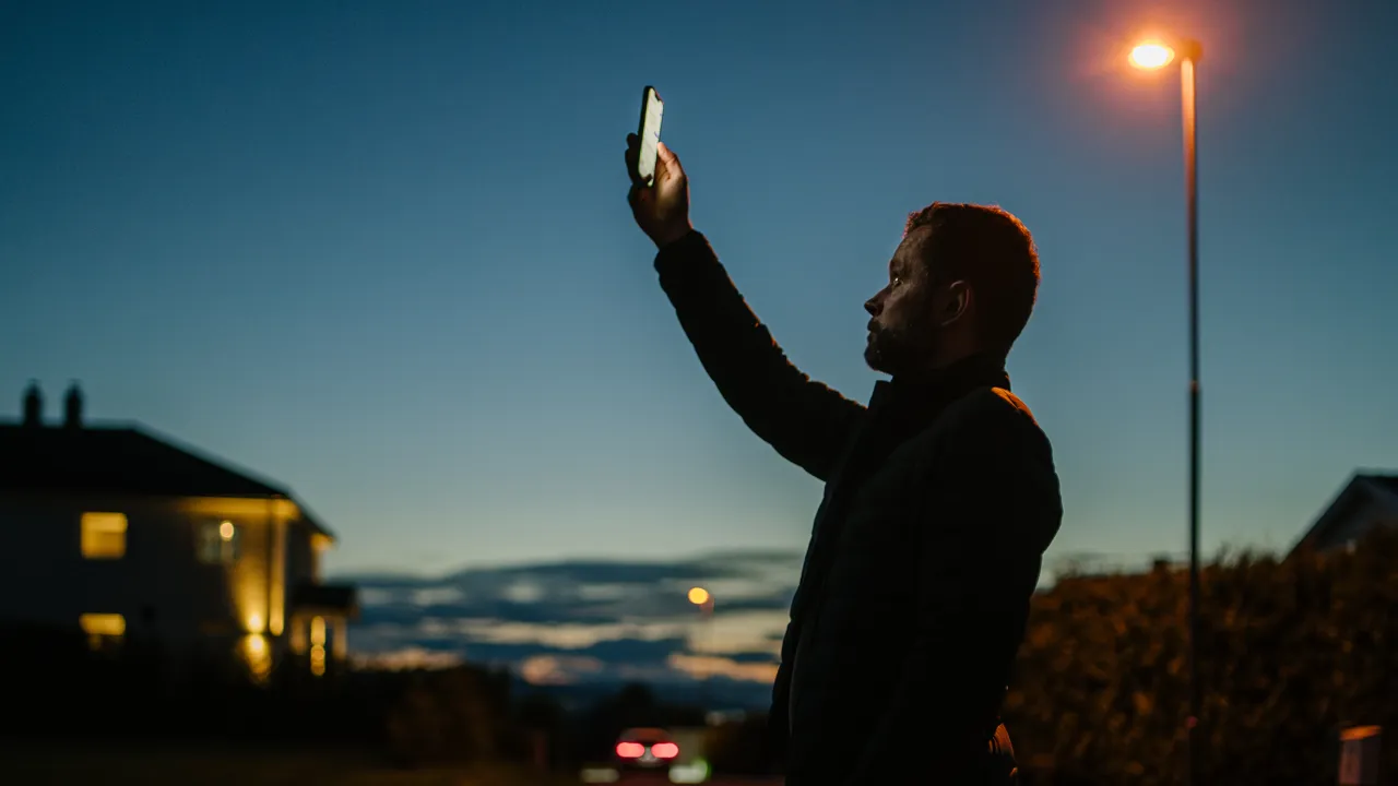 En mann som holder en mobiltelefon opp i luften.