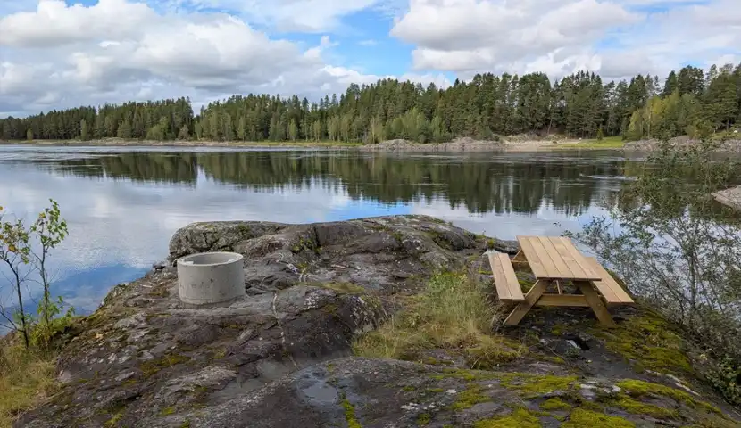 Et piknikbord på en stein ved siden av et vann.