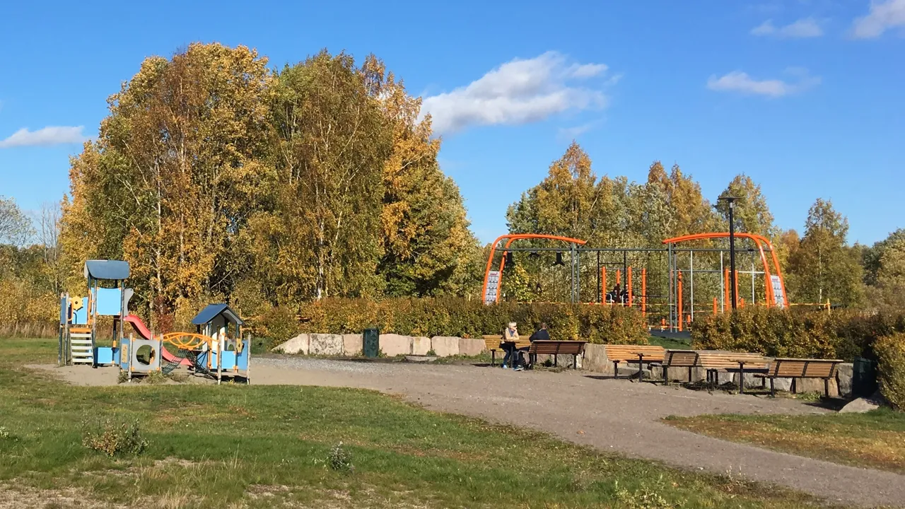 En park med lekestruktur og piknikbord.