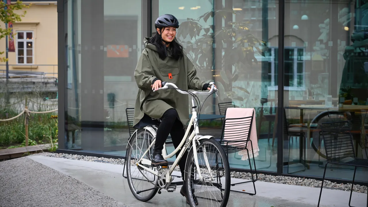 En kvinne sykler foran en bygning.