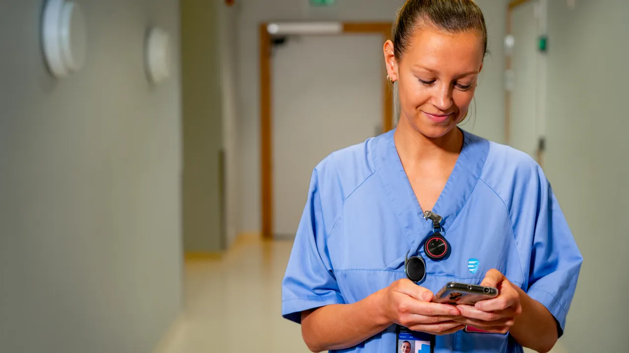 Sykepleier ser på mobilen.