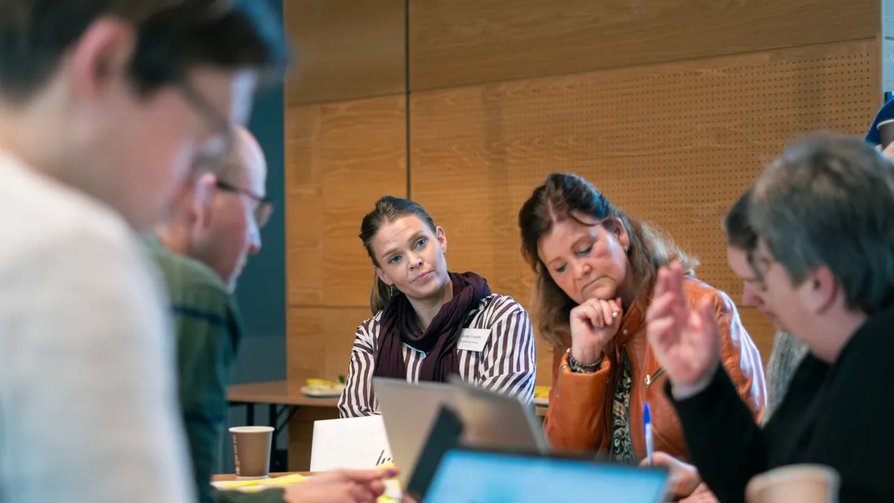 En gruppe mennesker som sitter rundt et bord med bærbare datamaskiner.