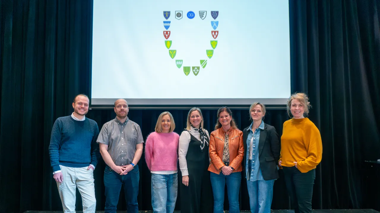 En gruppe mennesker som står foran et projektorlerret.