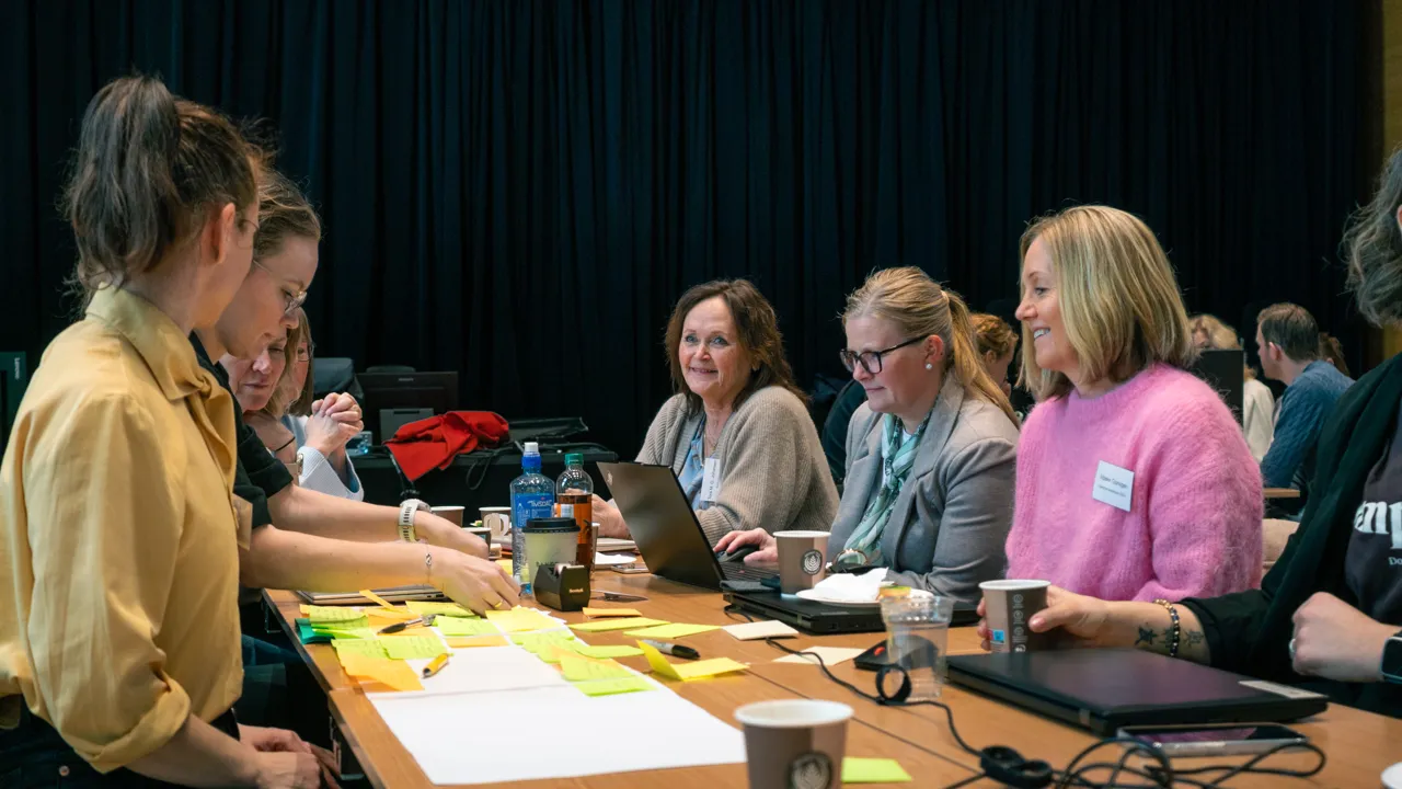 En gruppe mennesker som sitter rundt et trebord.