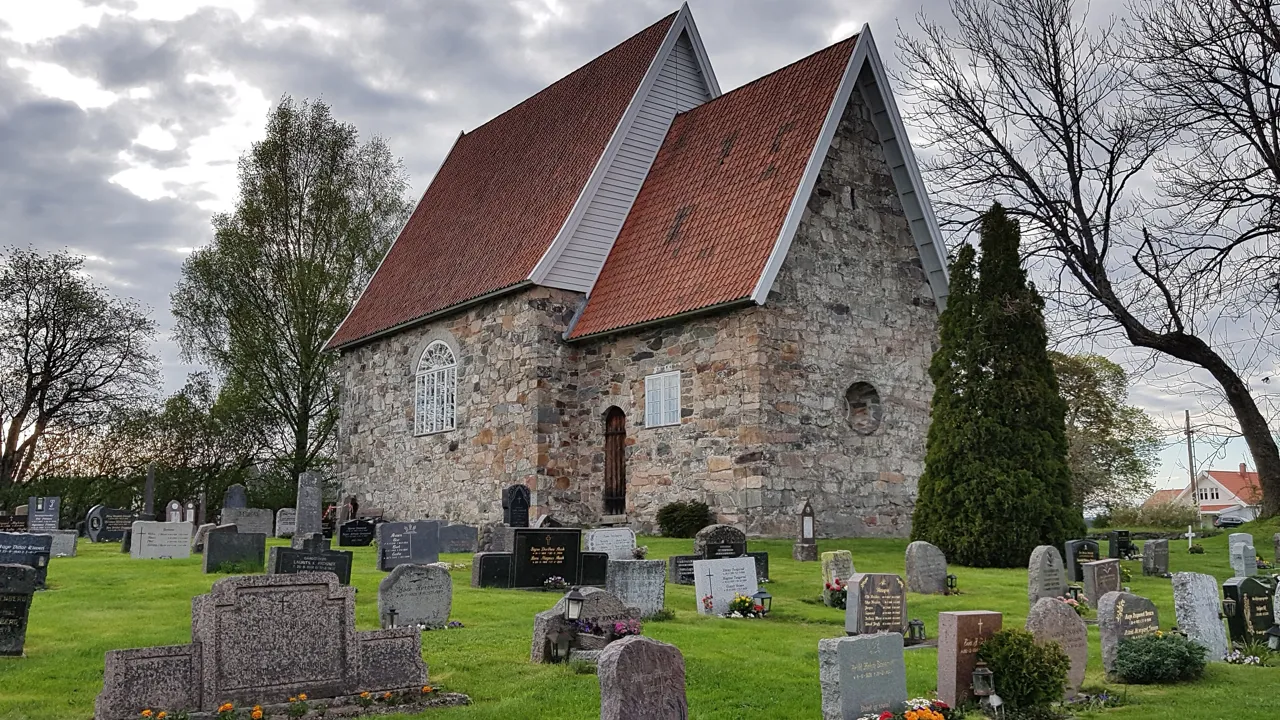 En kirke med rødt tak og en kirkegård.