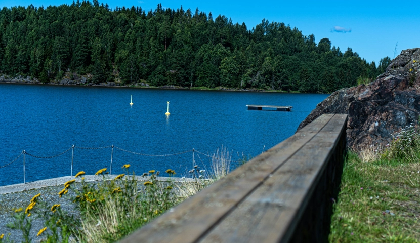 En trebenk som sitter ved siden av et vann.