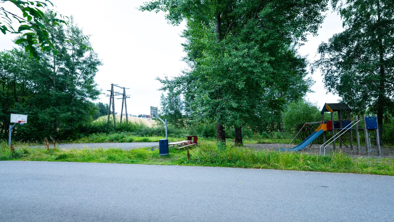 En park med lekeplass og basketballkurv.