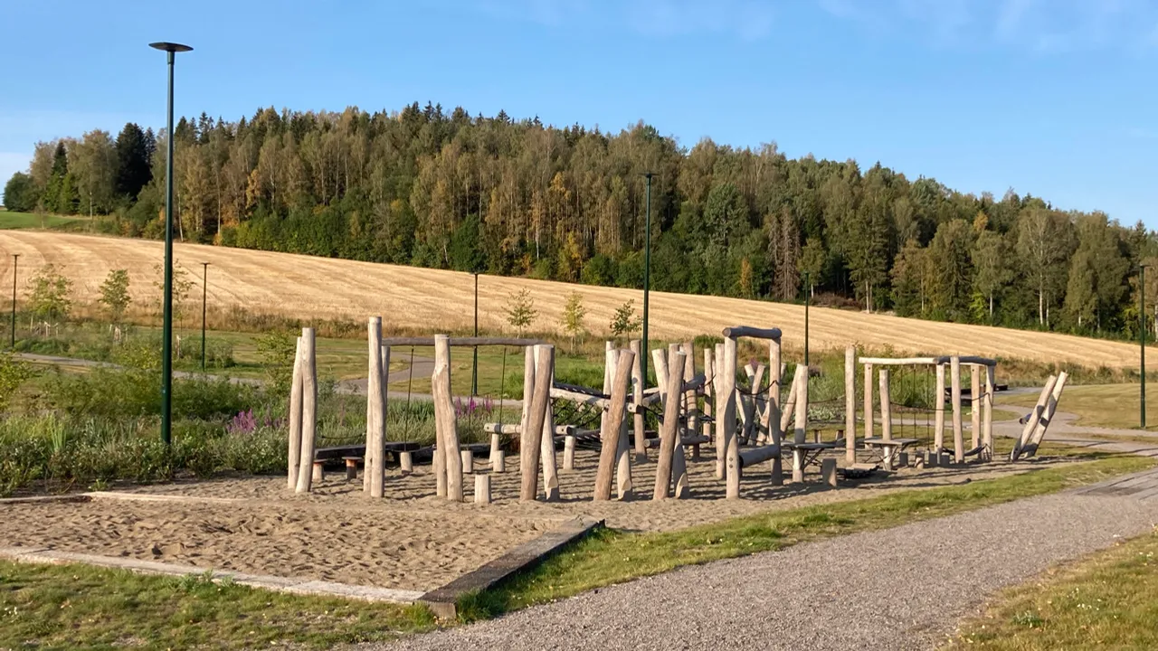 En park med en grussti og en trekonstruksjon.