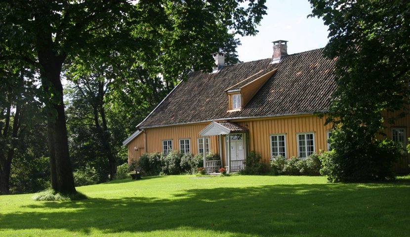 Et gult hus med en stor plen foran seg.