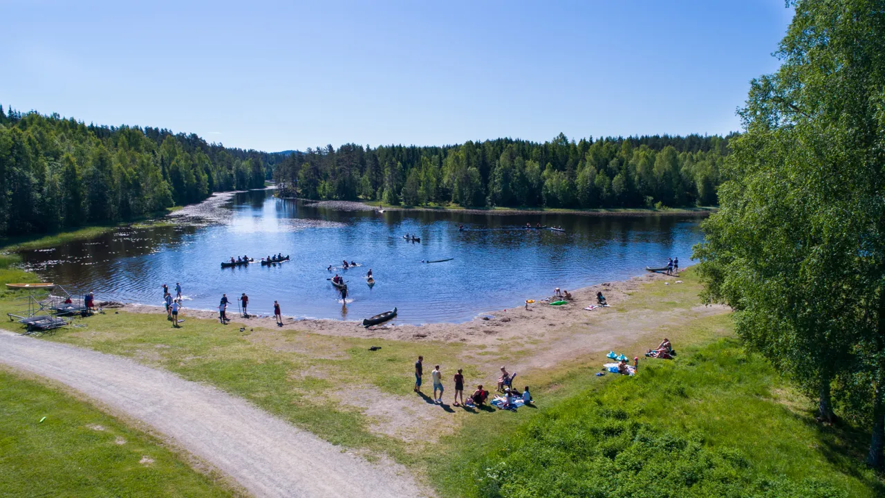 En gruppe mennesker som står ved bredden av en innsjø.