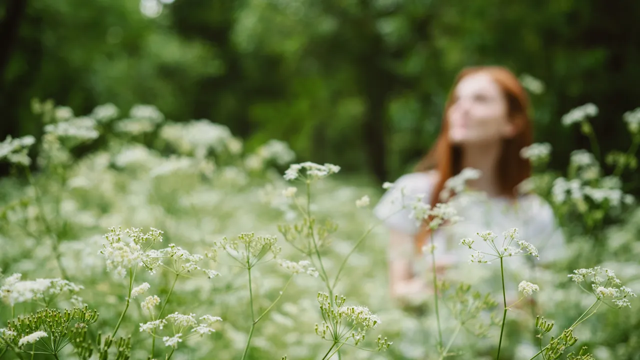 En kvinne står i et felt av hvite blomster.