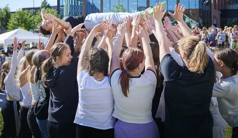 Mange unge mennesker holder en person som ligger over seg