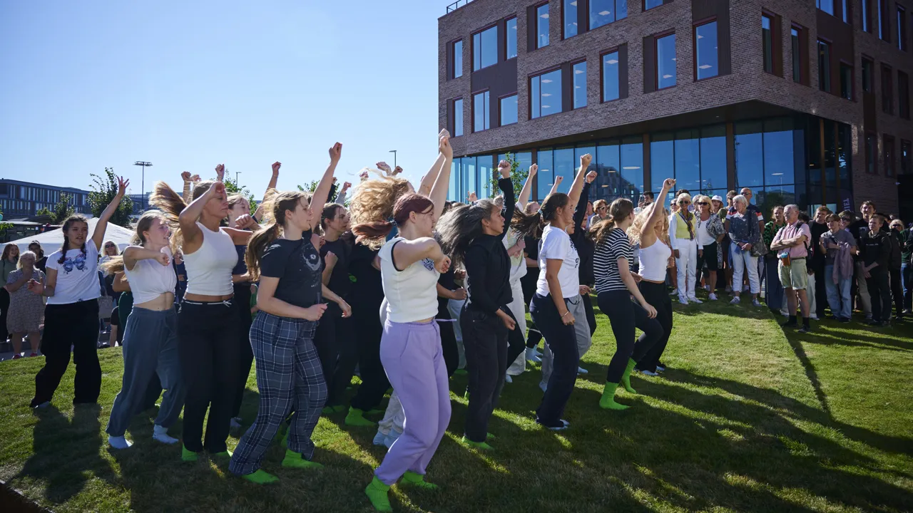 Mange unge mennesker hopper i danser i en park