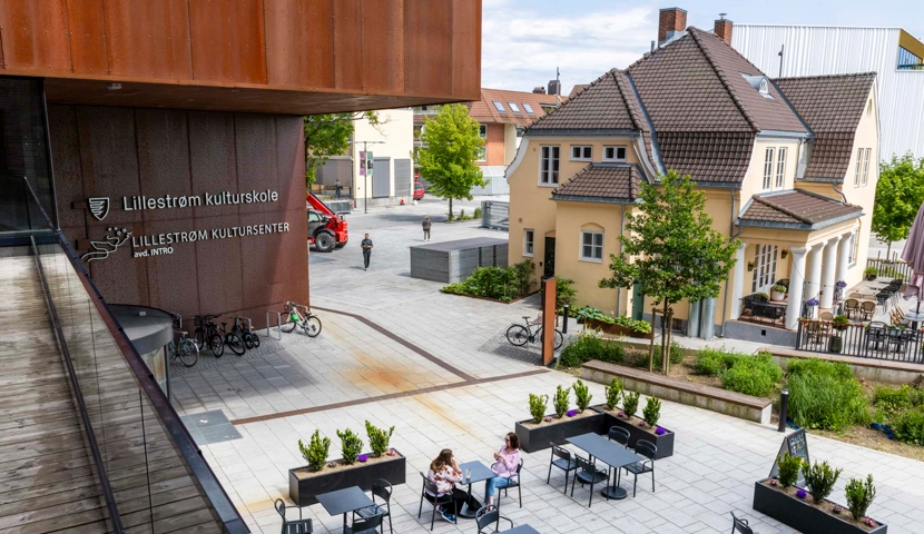 En gruppe mennesker som sitter ved bord utenfor en bygning.