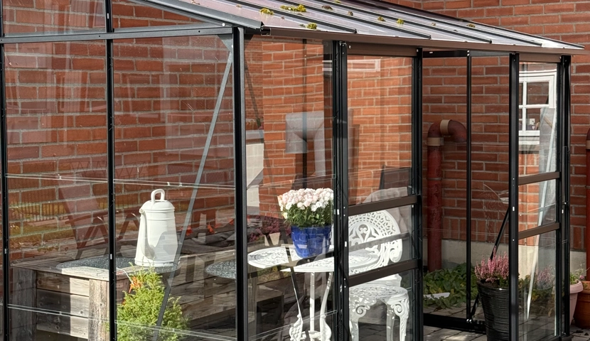 En uteplass med bord og stoler foran en murbygning.