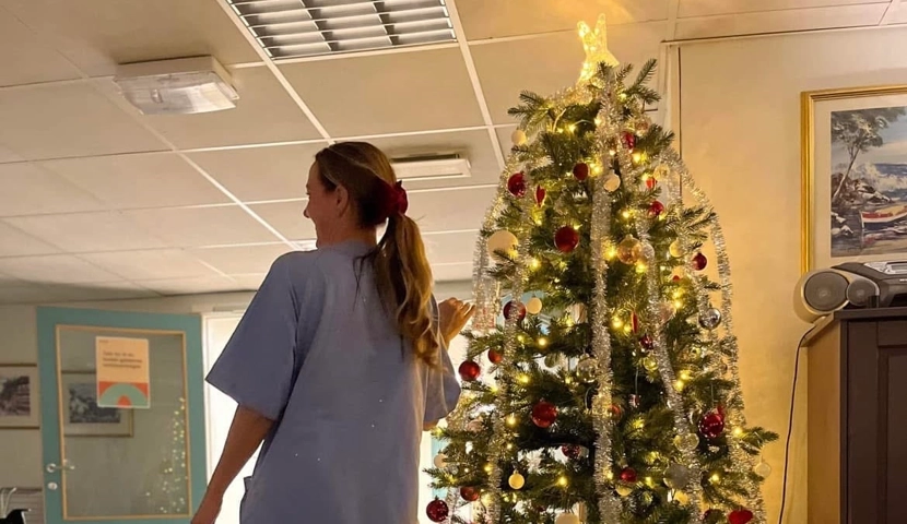 En kvinne står foran et juletre.