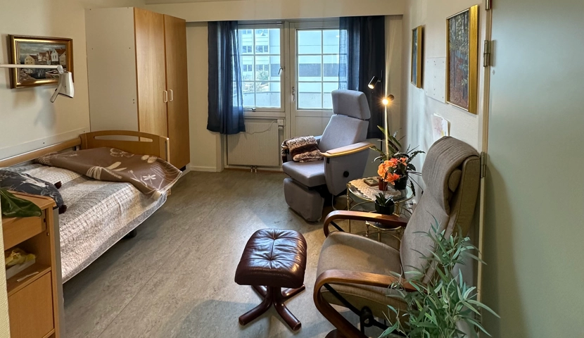 Et rom med seng, stol, skrivebord og en pult.