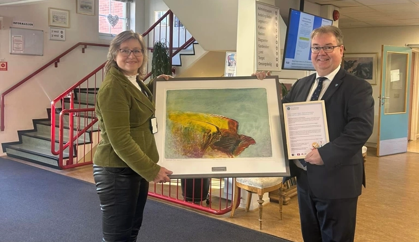 En mann og en kvinne holder opp et maleri.