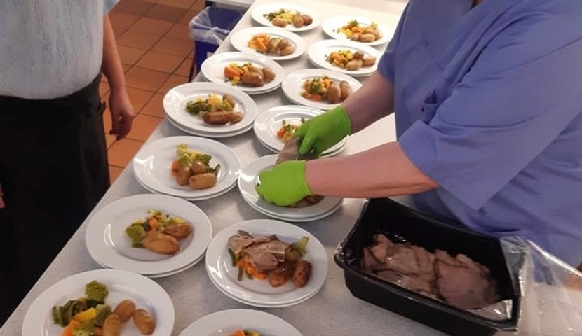 En person på et kjøkken som tilbereder mat på et bord.