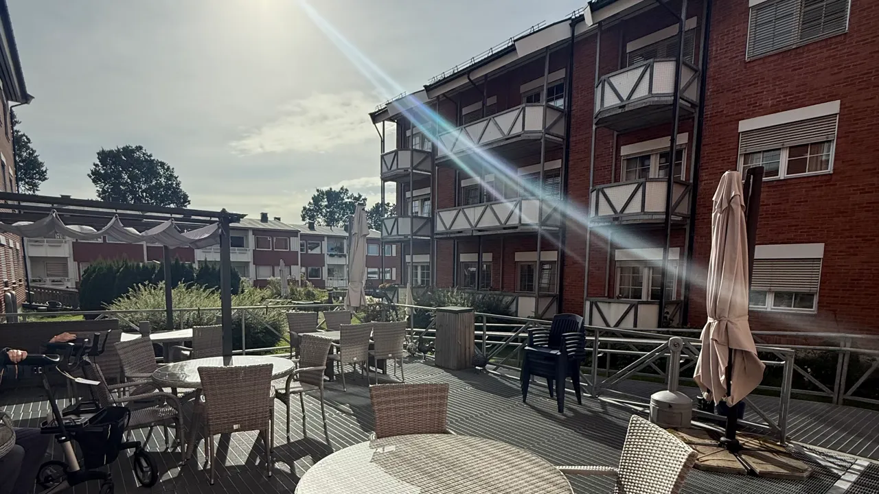 En uteplass med bord, stoler og parasoller.