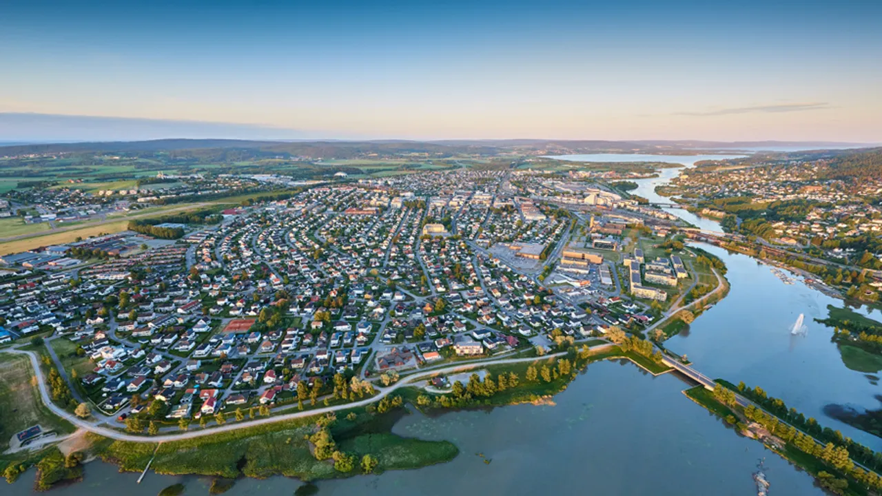 Et luftfoto av en elv og grønn natur og tett boligbebyggelse i bakgrunnen