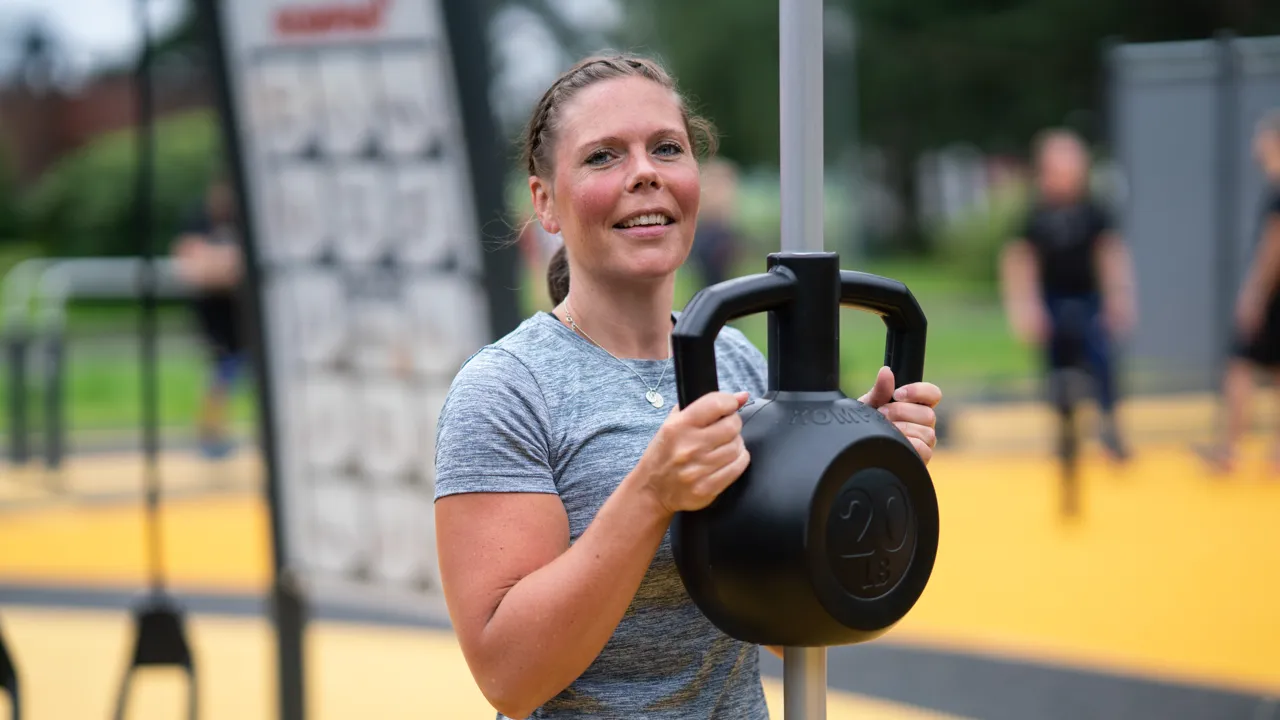 En kvinne holder en vekt på en stolpe.