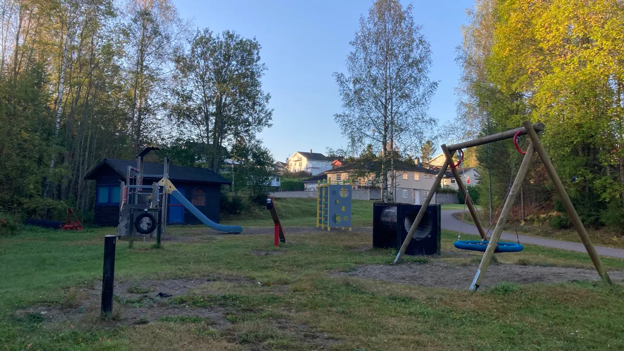 En lekeplass med huskestativ og sklie.