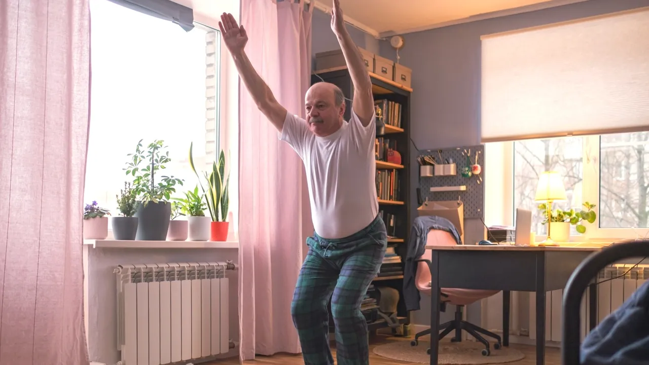 Mann i yoga-stilling i egen stue.