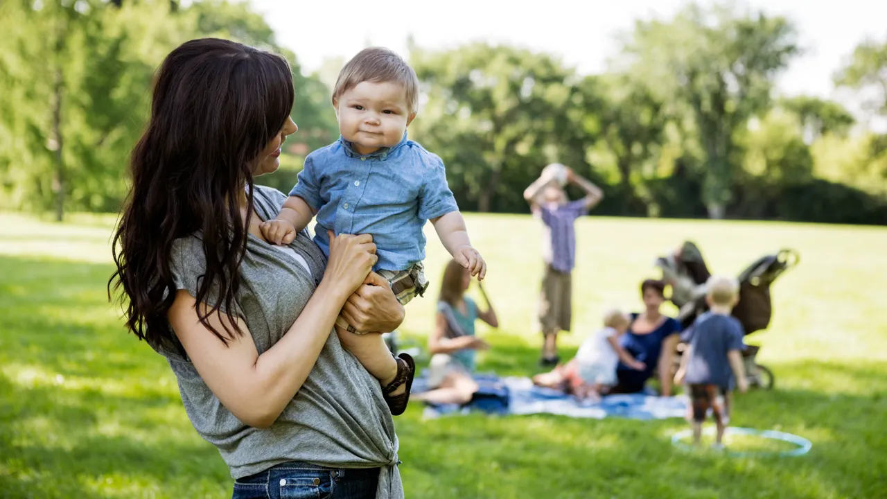 En kvinne holder en baby i en park.
