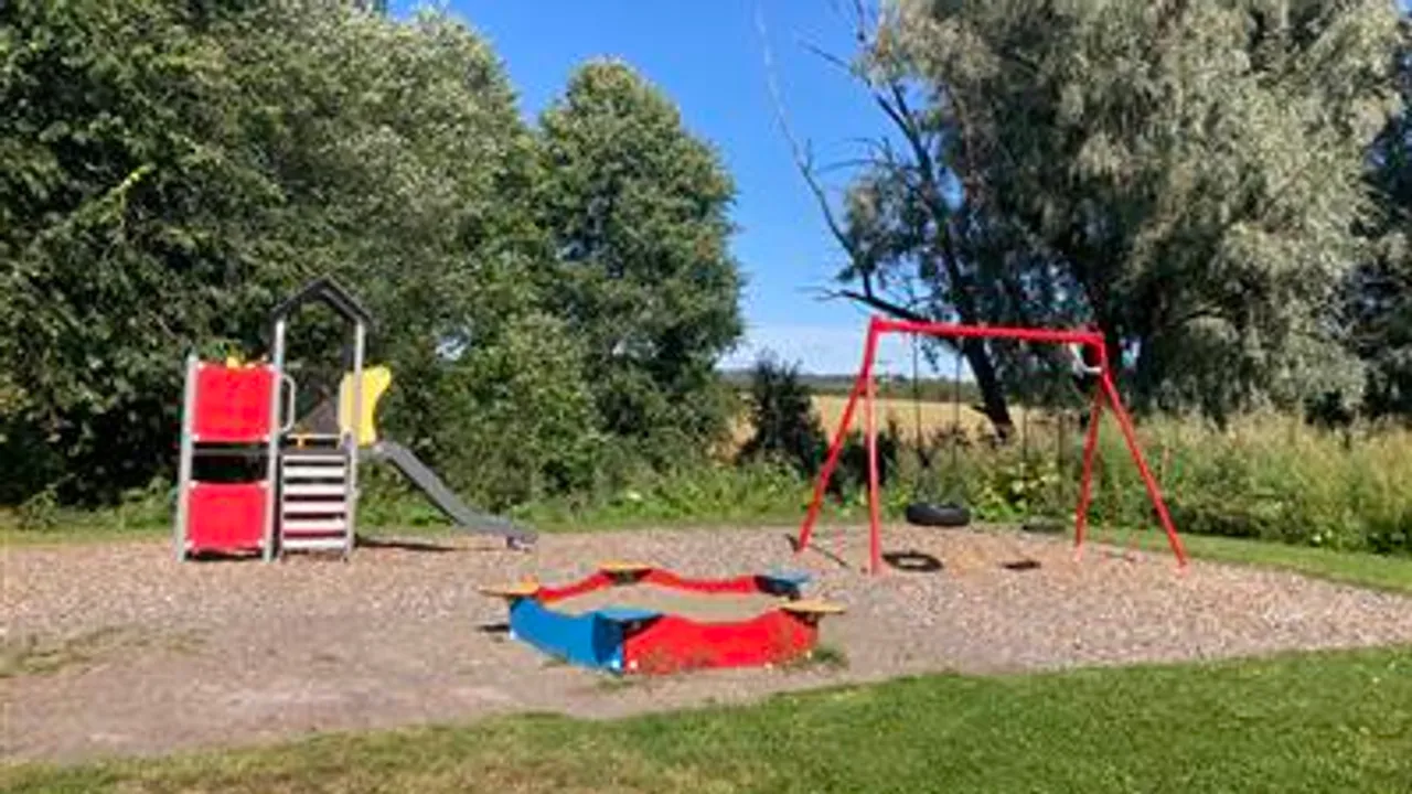 En lekeplass med huskestativ og sklie.
