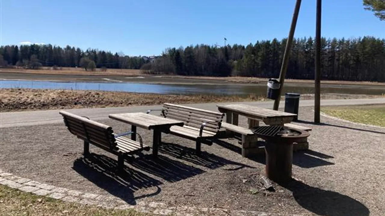 Et piknikbord , grill og benker nær en innsjø