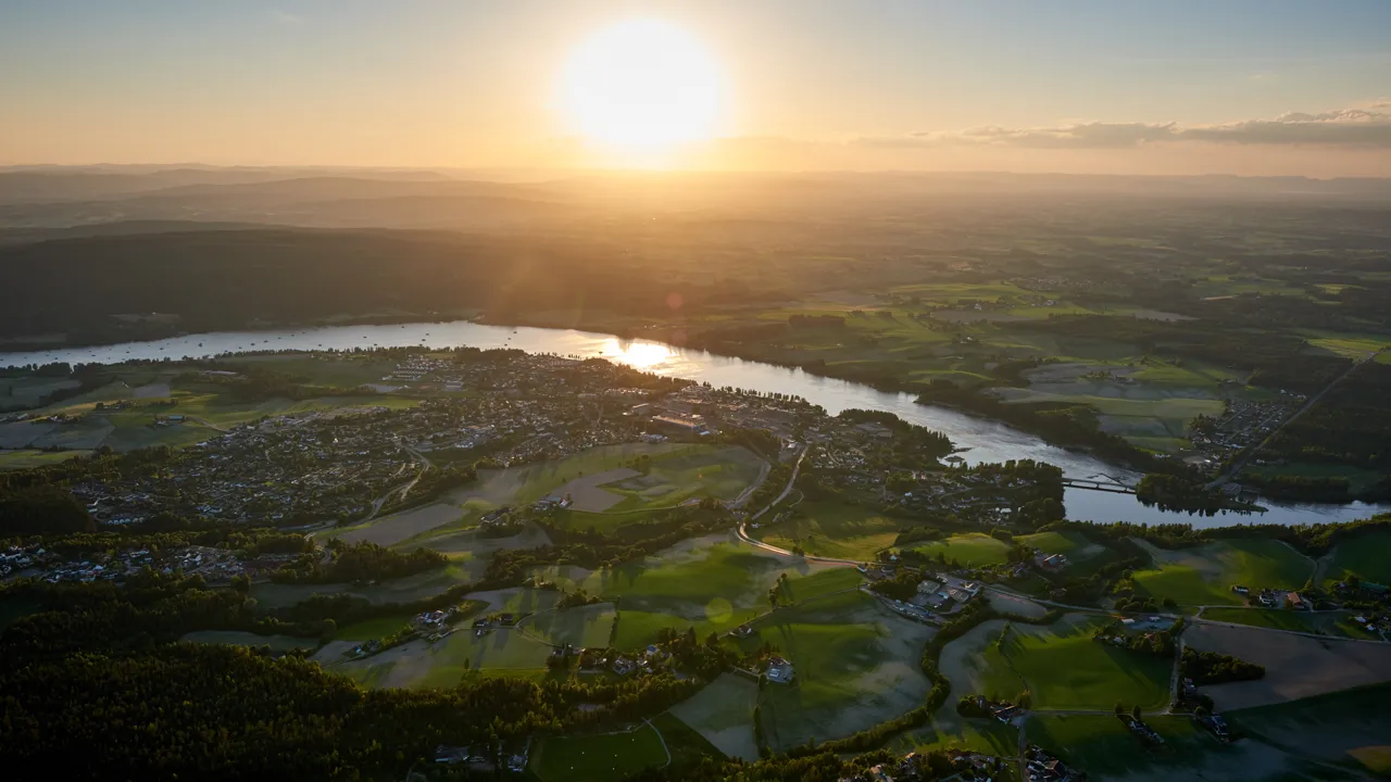 Et luftfoto av en elv og grønn natur i solnedgang