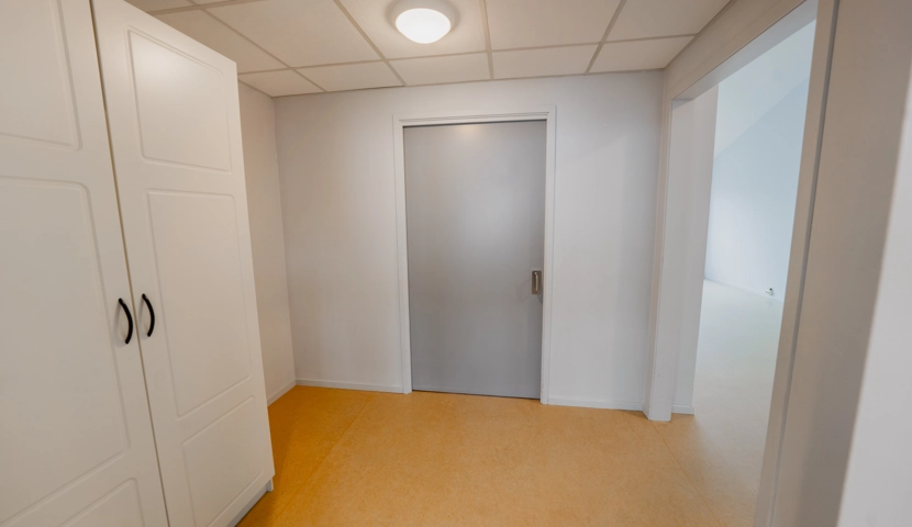 En gang med en hvit dør og hvite skap.