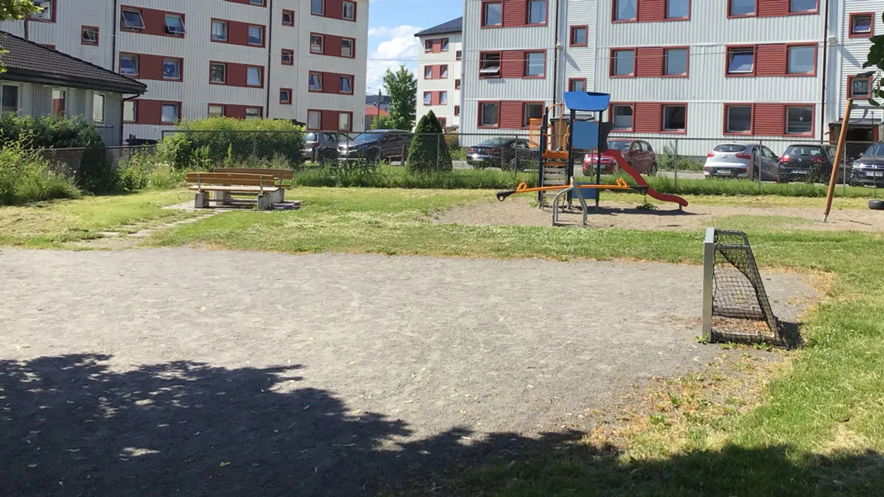 En lekeplass foran en stor boligblokk.