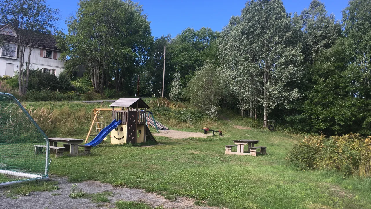 En park med lekeplass og piknikbord.