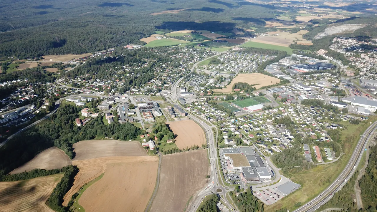 Et luftfoto av en by og en motorvei og landbruksområde
