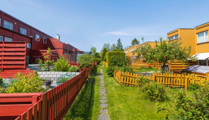 En rekke røde bygninger ved siden av en frodig, grønn åker.