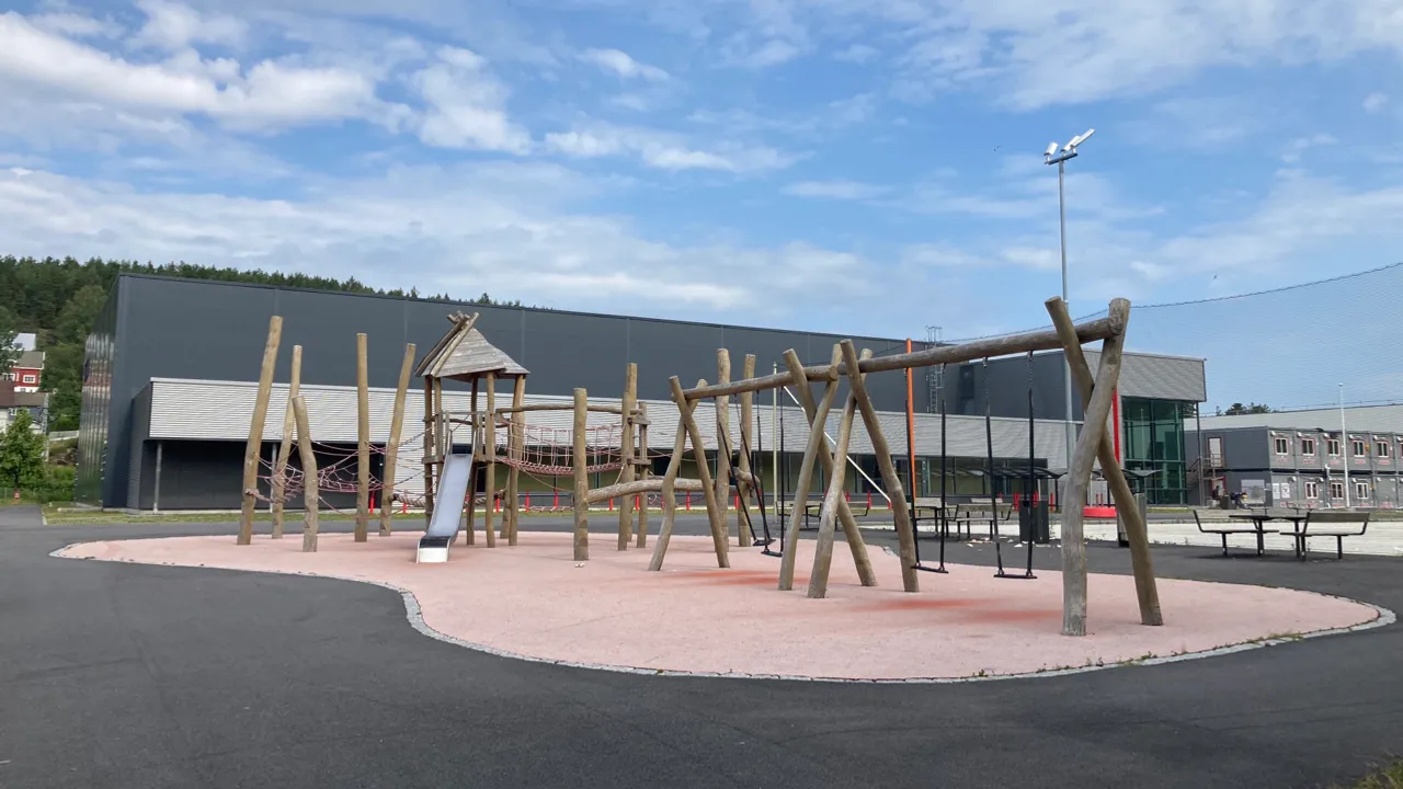 En lekeplass med en trekonstruksjon og en sklie.