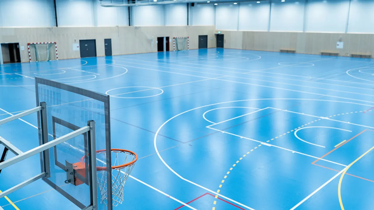 En innendørs basketballbane med basketballkurv.