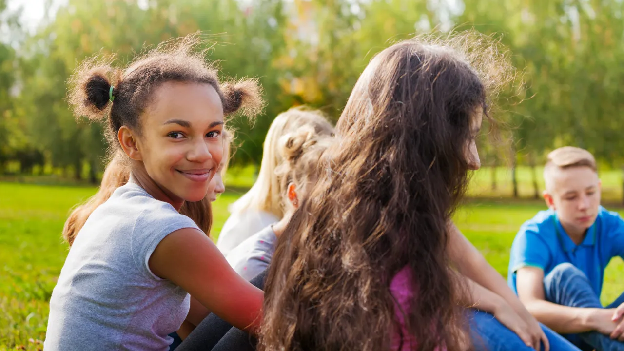 En gruppe ungdommer som sitter på gresset.