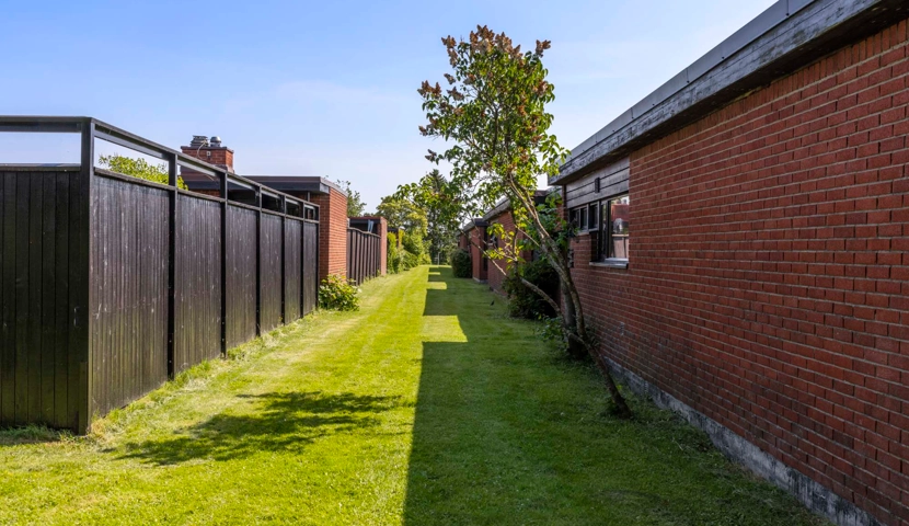 En gressplen ved siden av en murbygning.